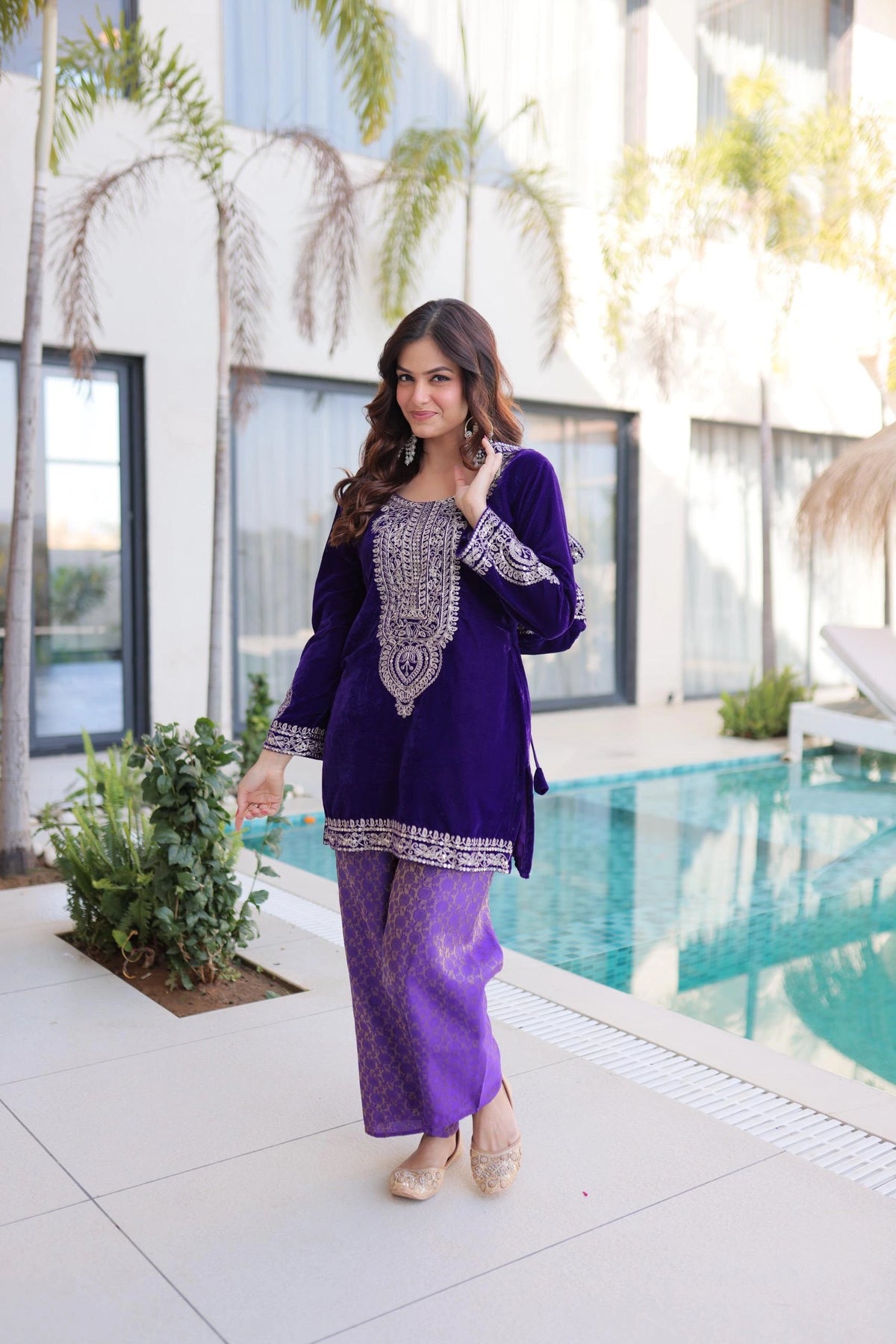Woman in a purple outfit standing by a pool with a modern building in the background