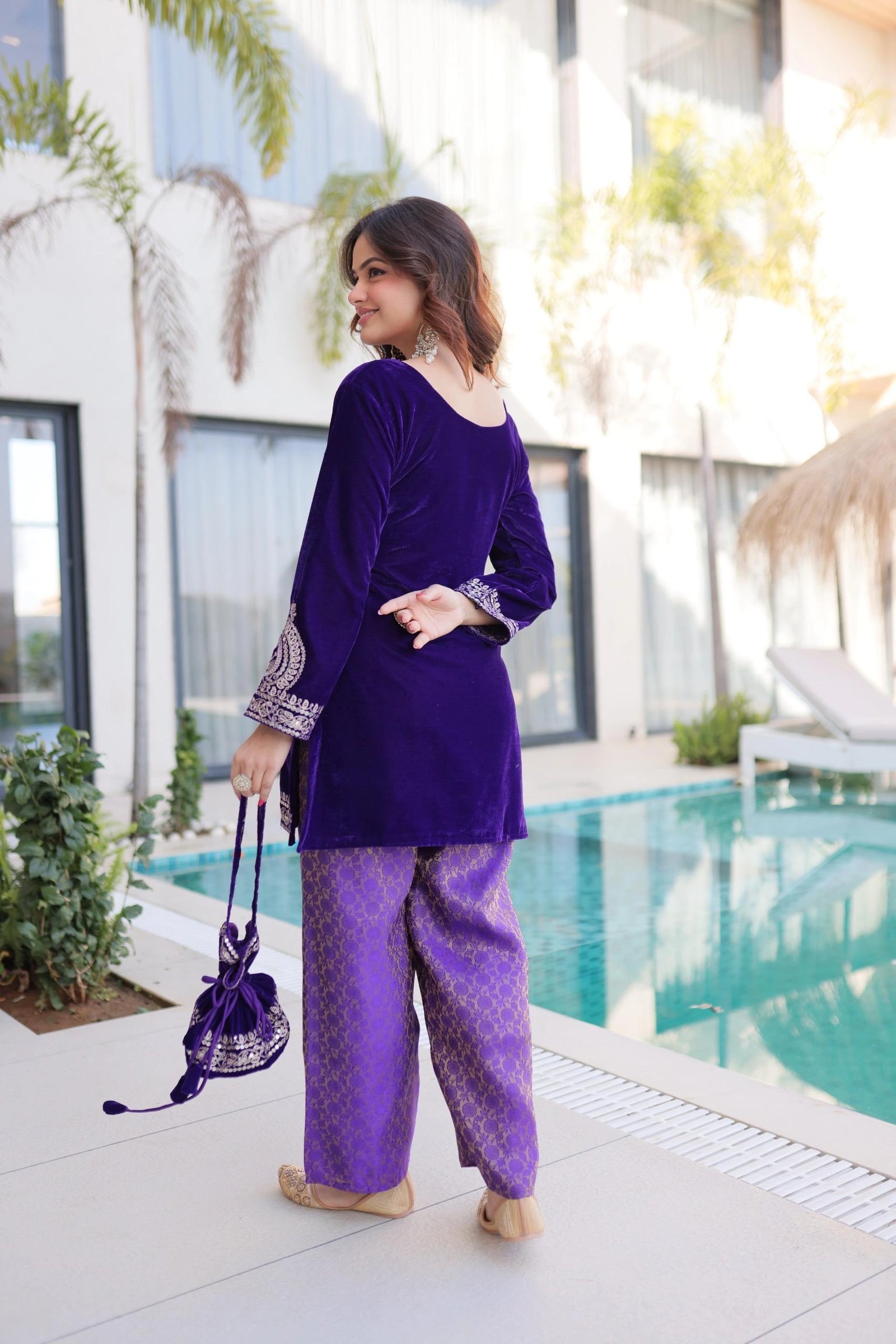 Woman in a purple outfit standing by a pool