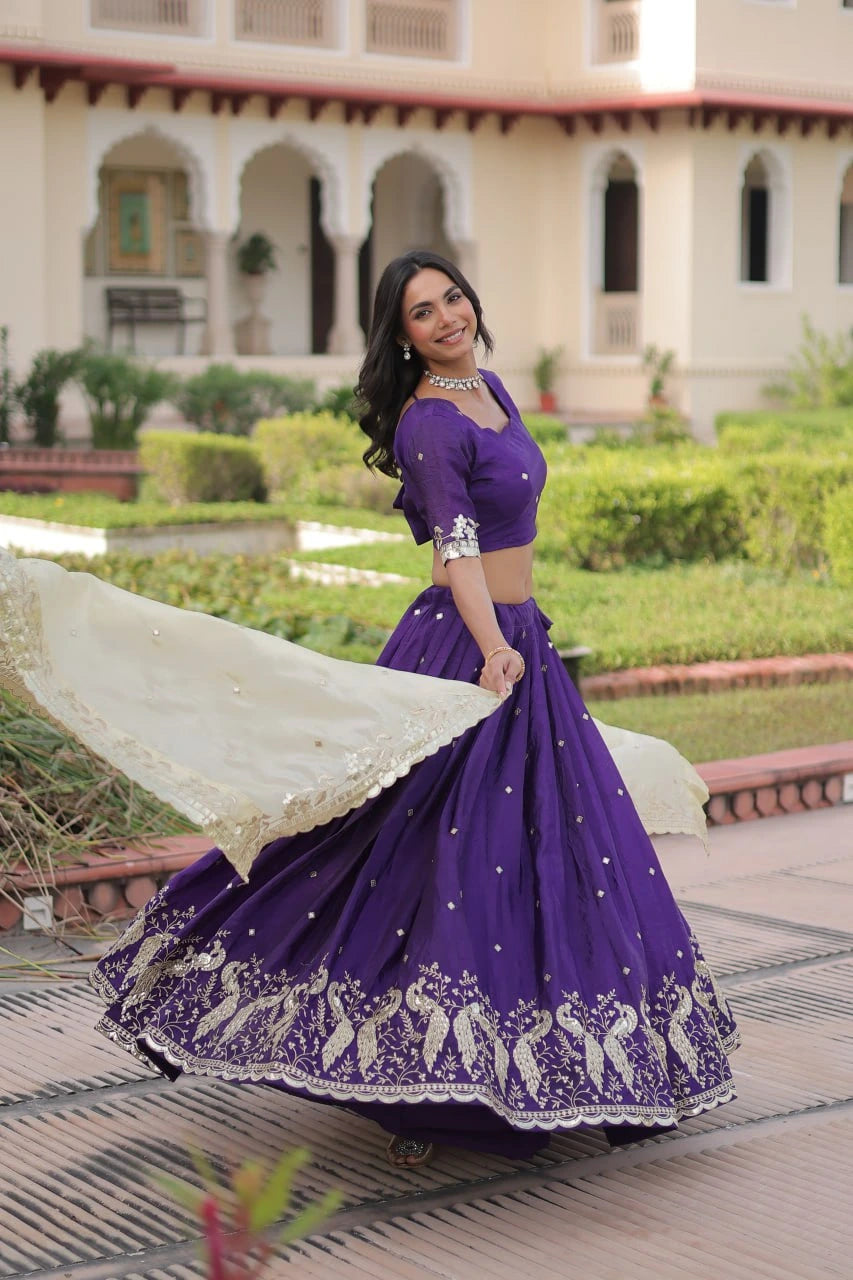 Woman in a purple traditional outfit with white embroidery standing in front of a building with arches.