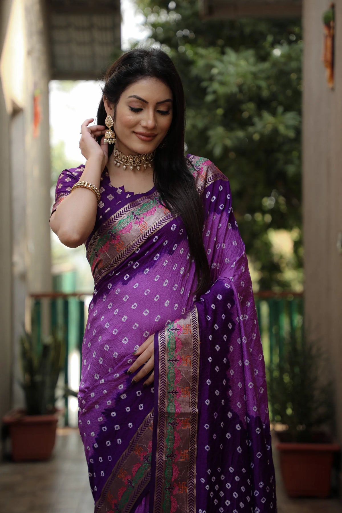 Woman in a purple saree with a blurred outdoor background