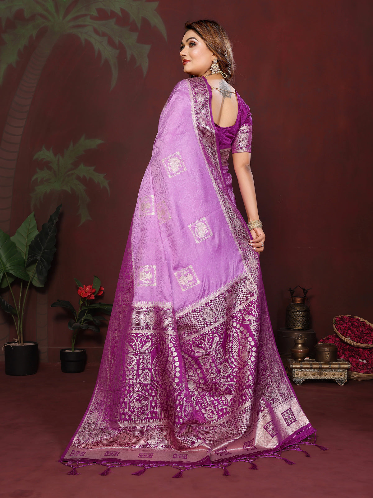 Woman wearing a purple saree with intricate patterns on a dark background