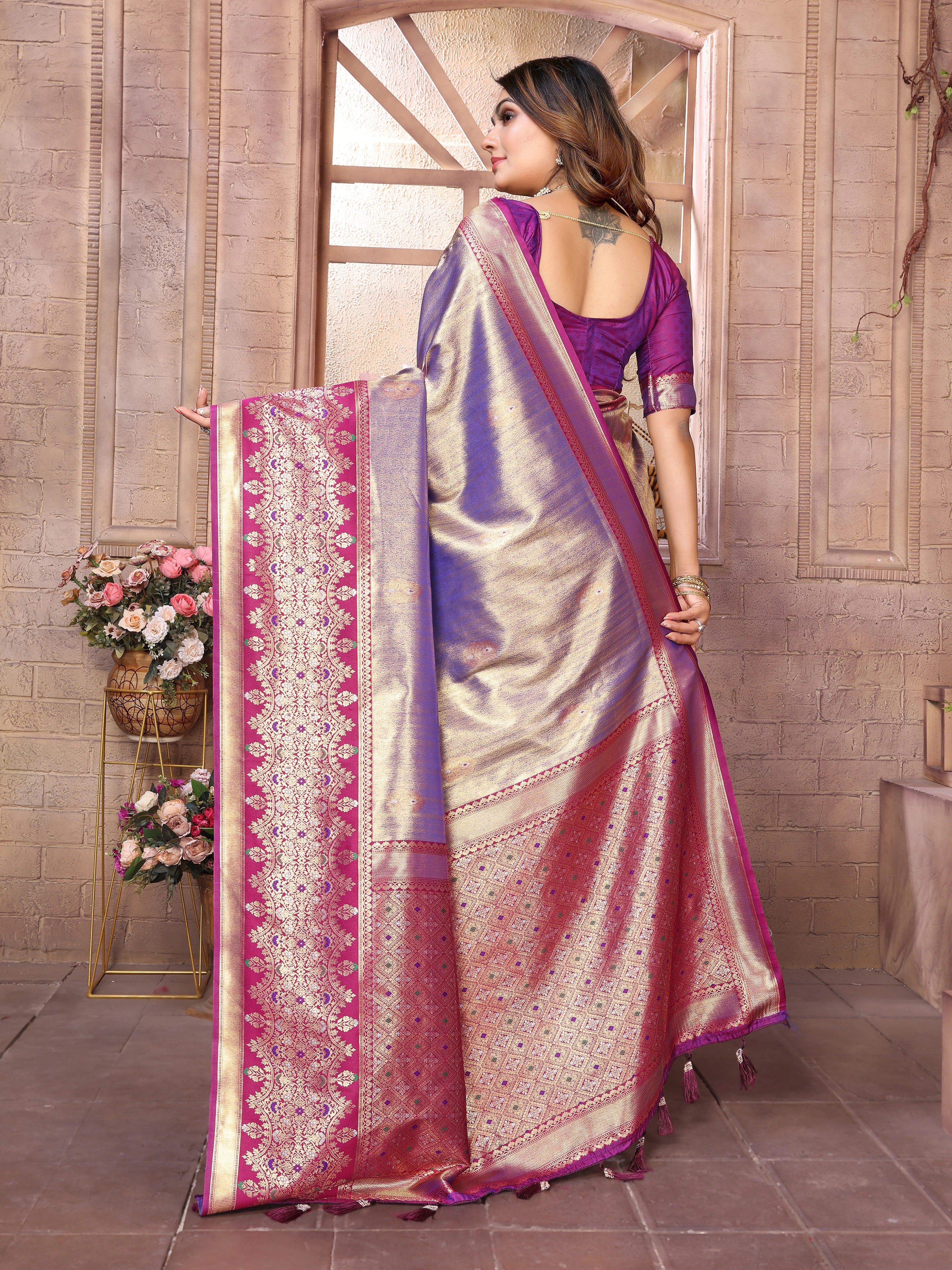 Woman holding a traditional saree with intricate patterns in a decorative setting.