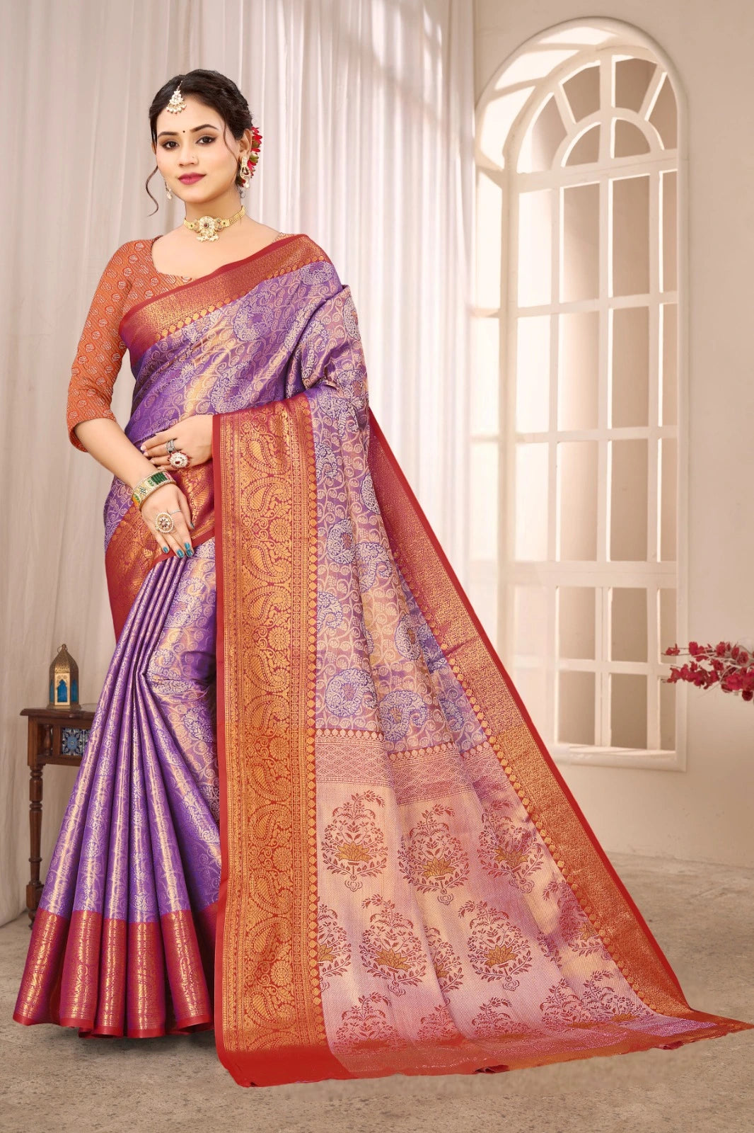 Woman wearing a traditional saree with a purple and orange pattern in a well-lit room.