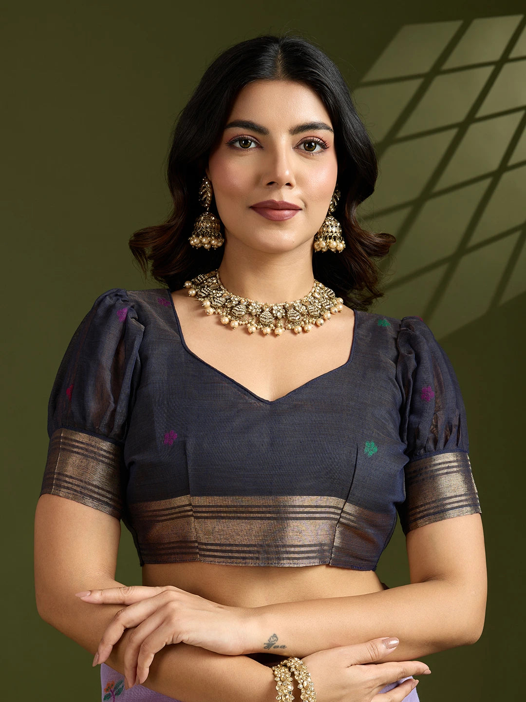 Woman wearing a traditional outfit with jewelry against a green background
