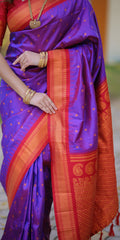 Woman wearing a vibrant purple and orange saree with gold jewelry.