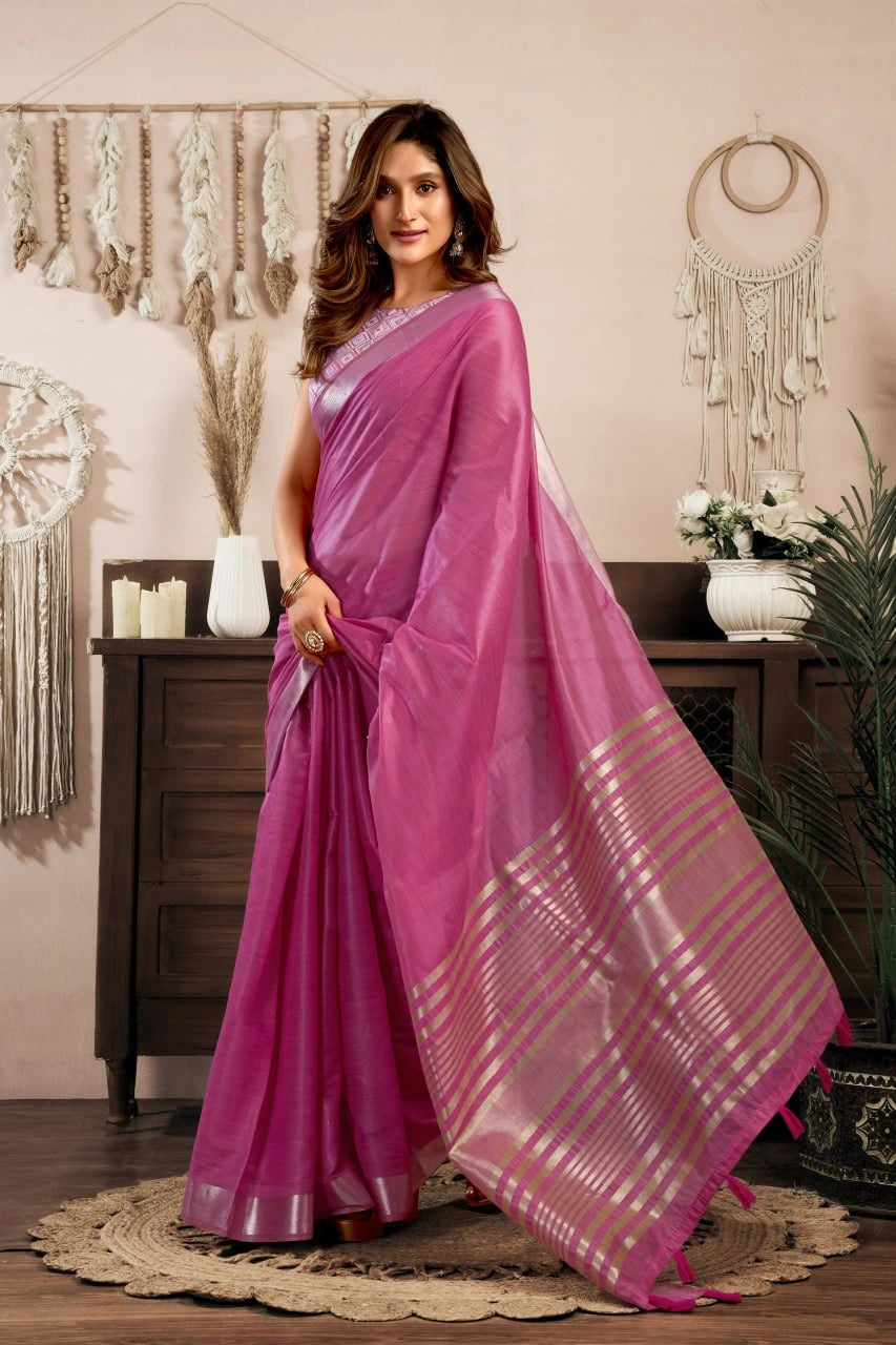 Woman wearing a pink saree in a decorated room with plants and decor.