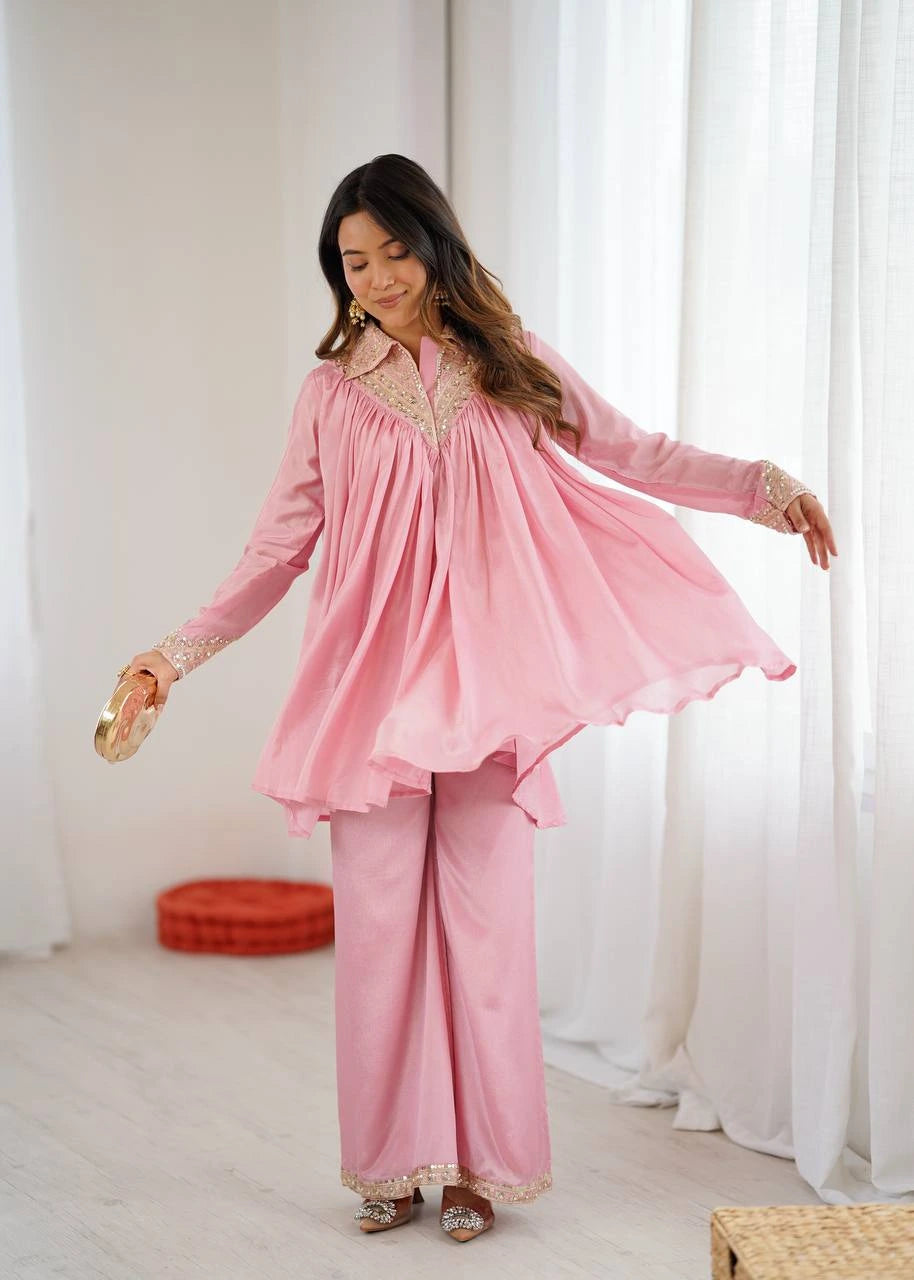 Woman wearing a pink traditional outfit in a bright room with white curtains.