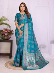 Woman wearing a teal saree with floral patterns indoors.