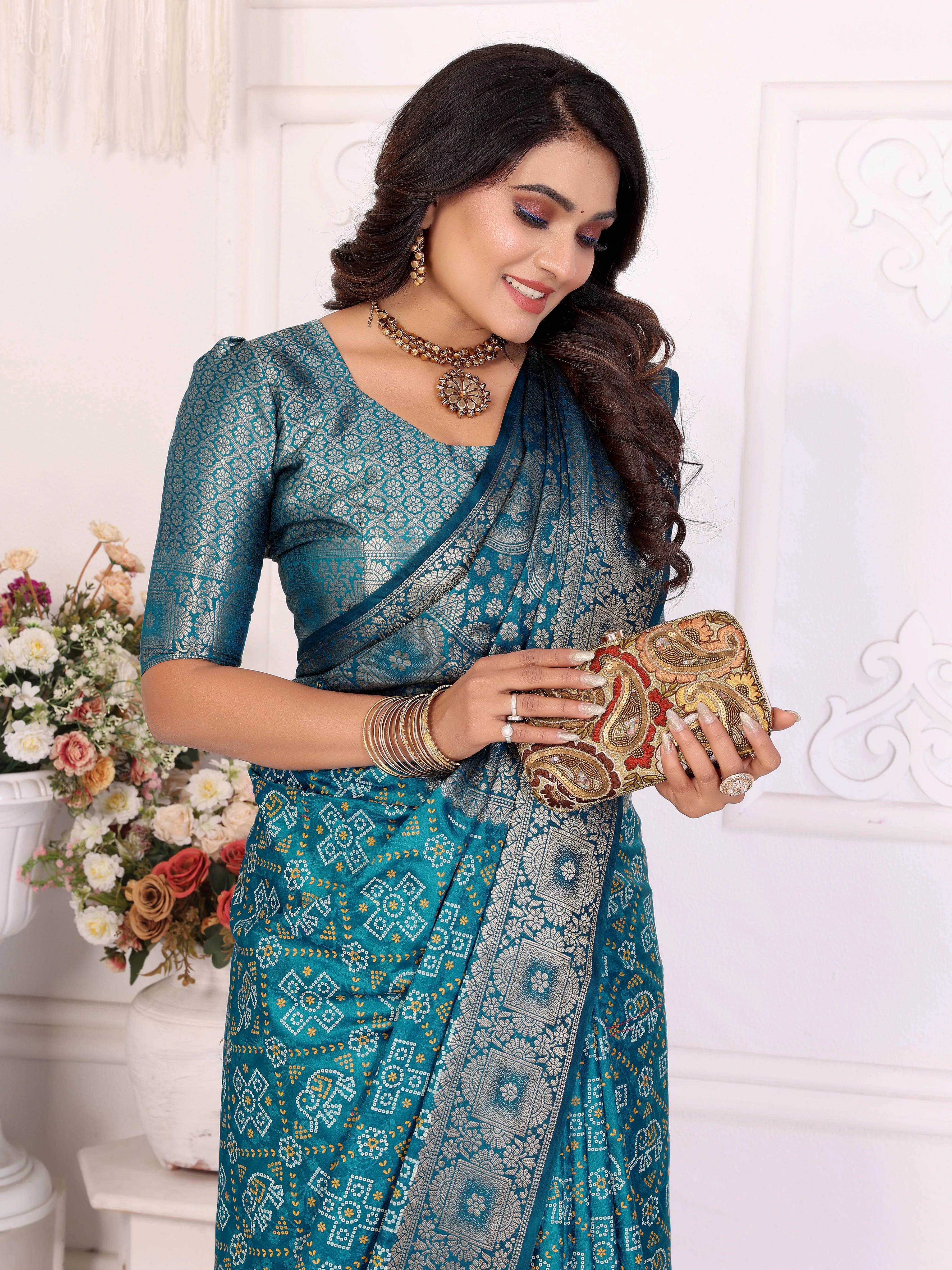 Woman in a blue saree holding a clutch against a white background