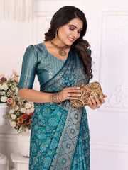 Woman in a blue saree holding a clutch against a white background