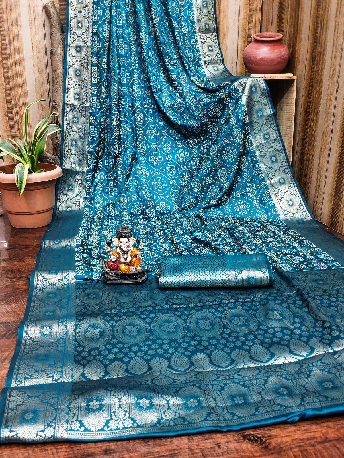Blue patterned fabric draped over a surface with decorative items on a wooden floor.