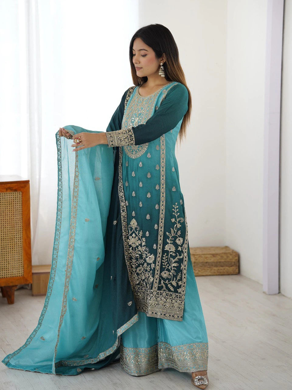 Woman holding a blue embroidered traditional outfit with a white background