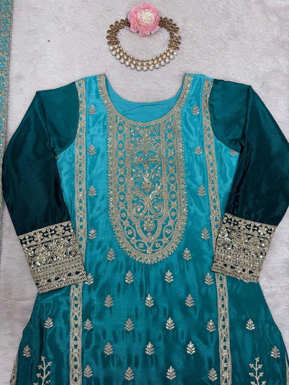 Teal embroidered dress with silver detailing on a light gray background