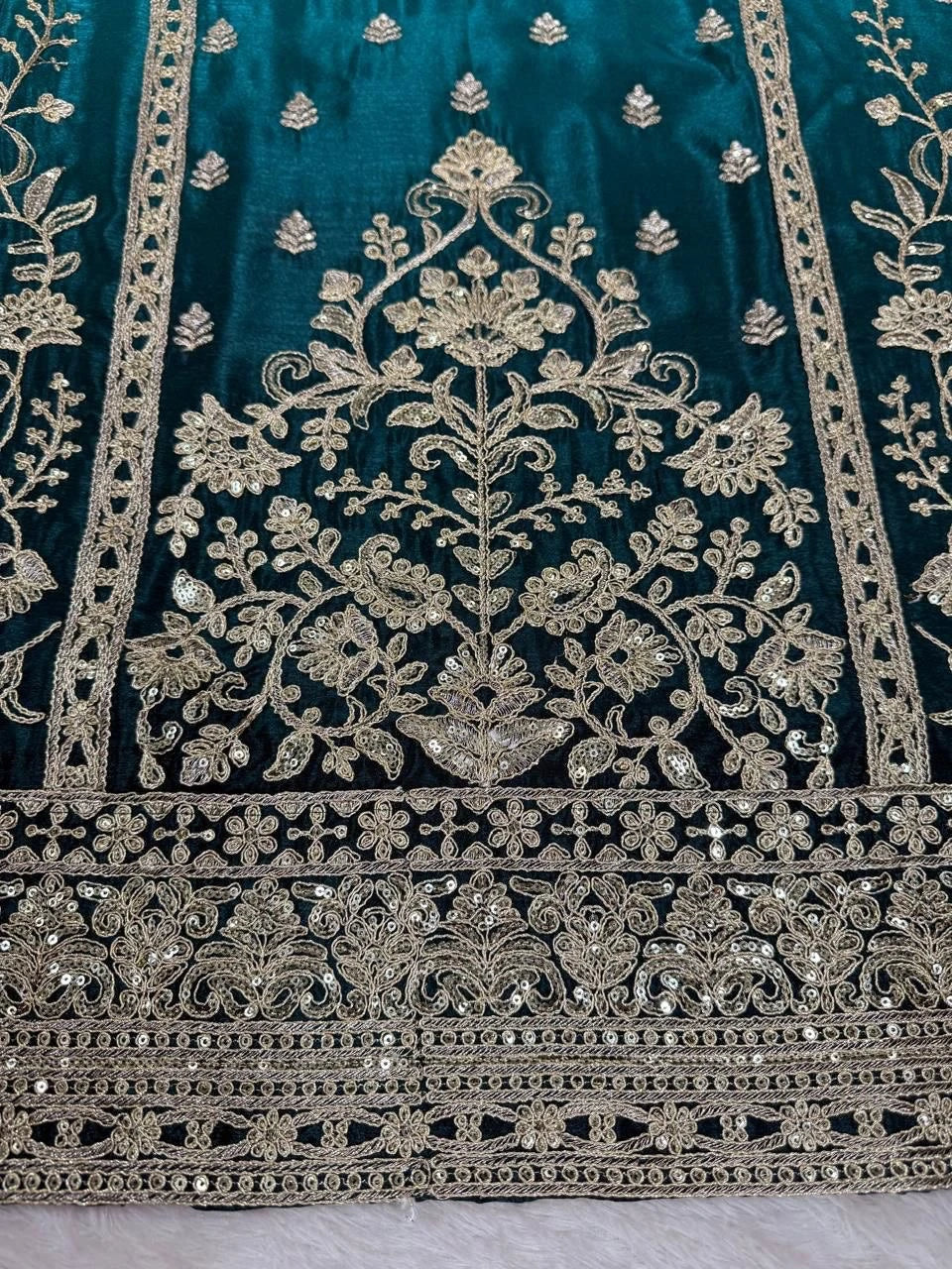 Decorative fabric with intricate gold embroidery on a teal background