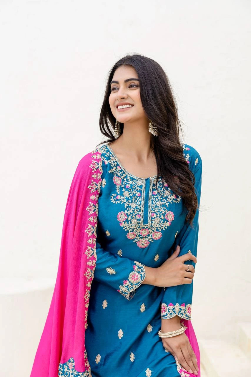 Woman wearing a blue embroidered saree with pink dupatta on a white background