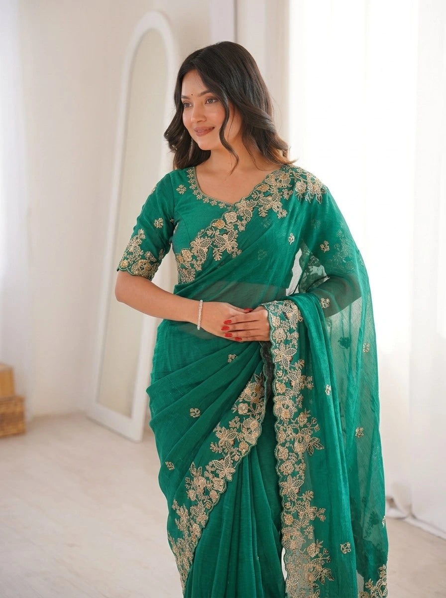 Woman wearing a green saree with floral patterns in a minimalistic setting