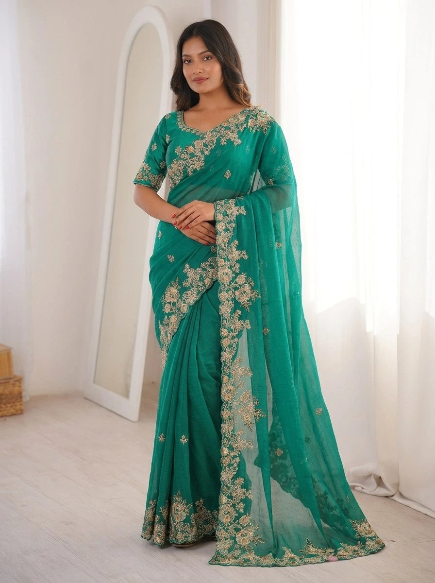 Woman wearing a green saree with gold embroidery in a minimal indoor setting