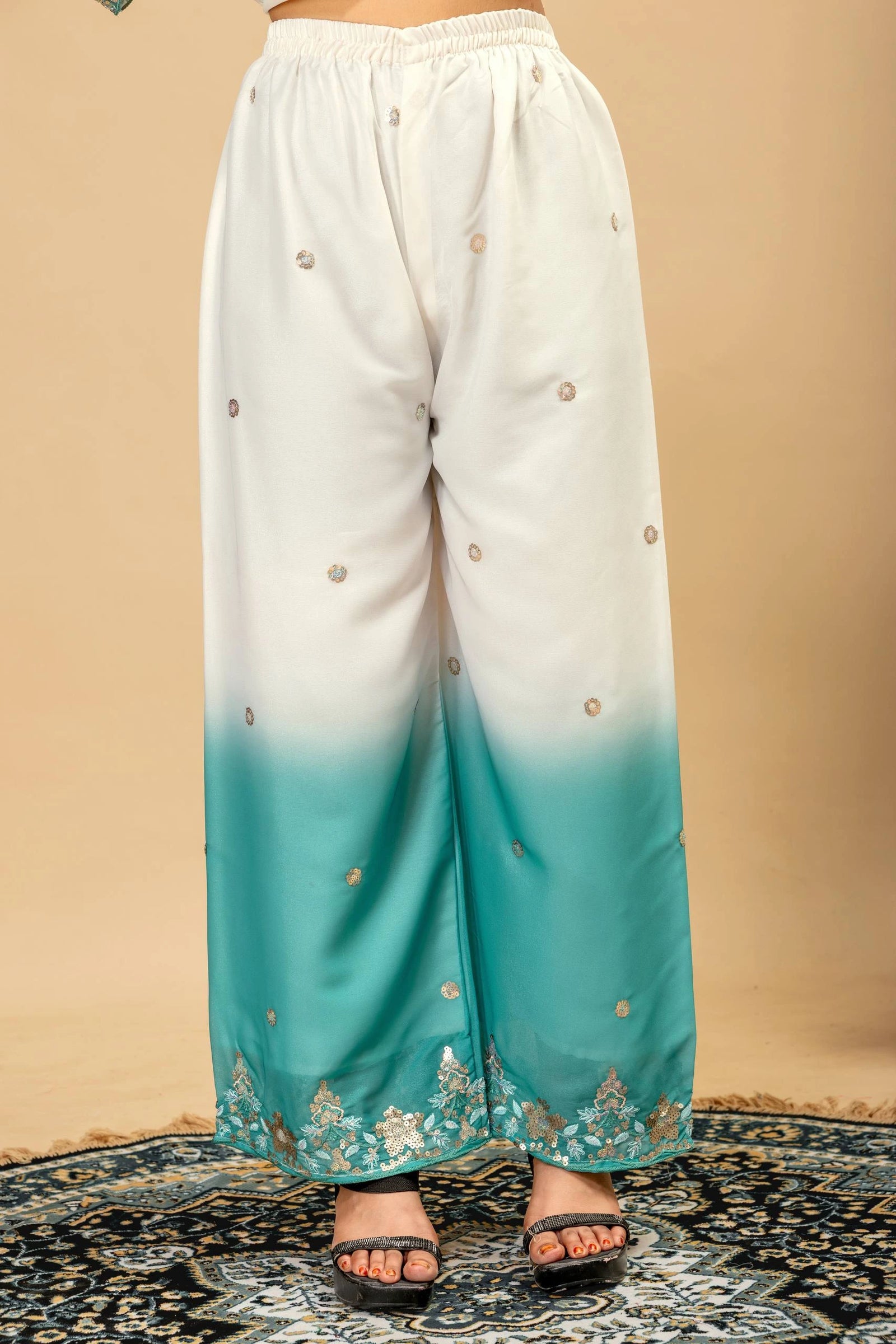 White and blue gradient pants with floral embroidery on a beige background