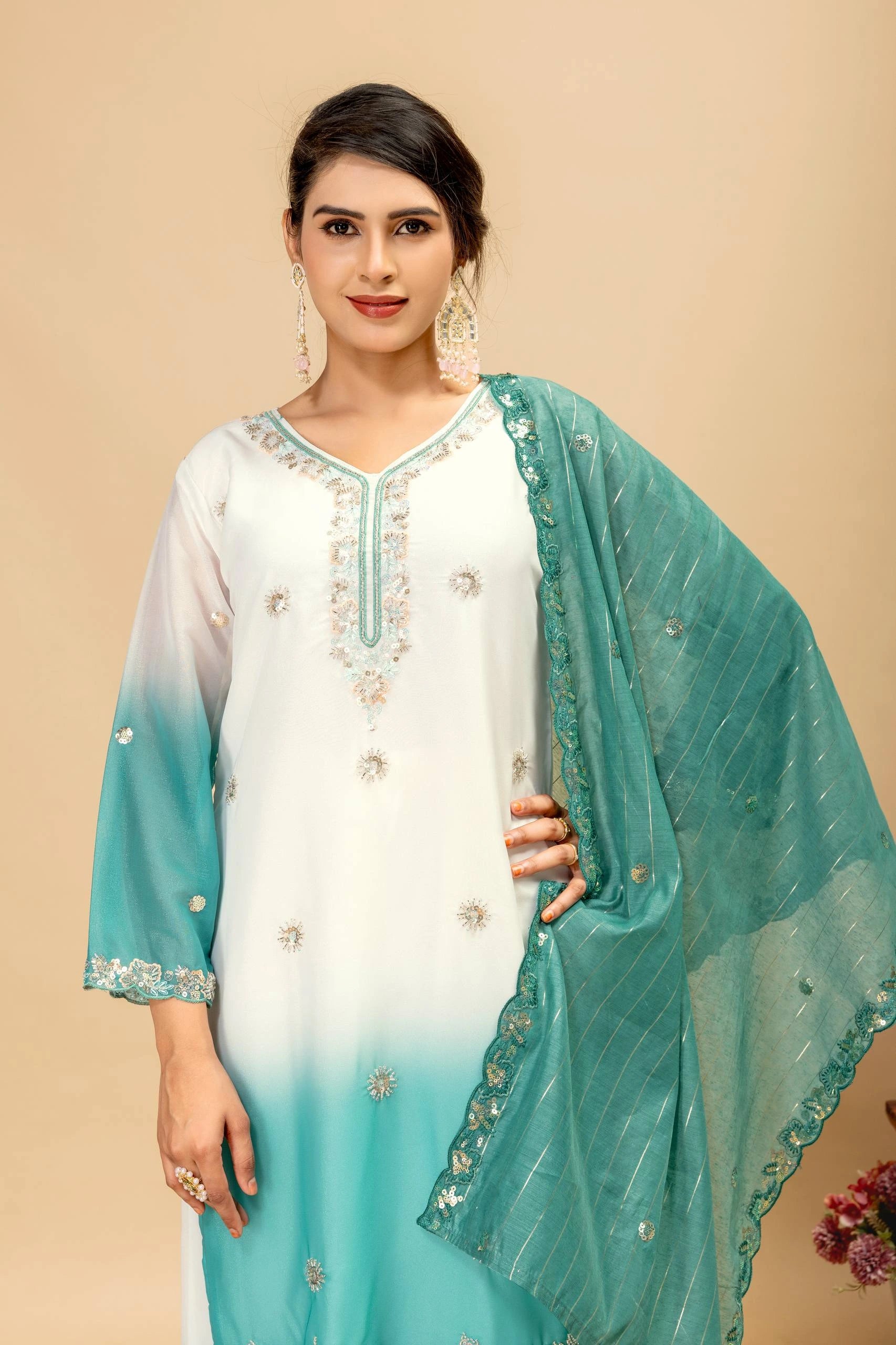 Woman wearing a white and teal traditional outfit with a beige background