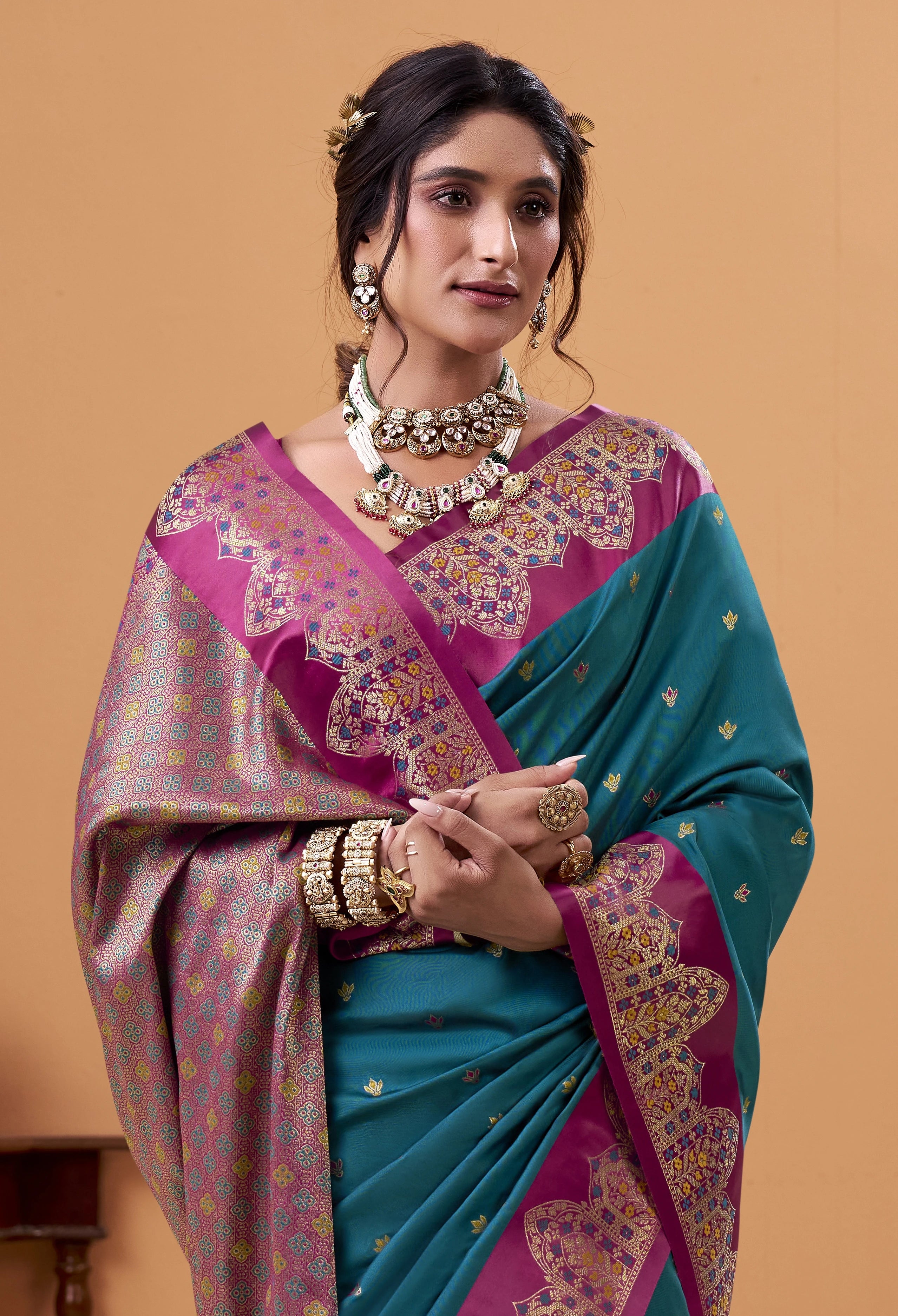 Woman wearing a traditional saree with intricate patterns on a beige background