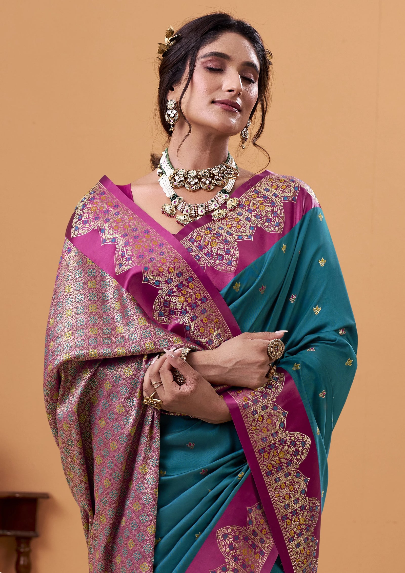 Woman wearing a traditional saree with a pink and blue color scheme on a beige background