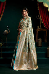 Woman in a traditional saree standing in a decorative setting with red curtains and green steps.