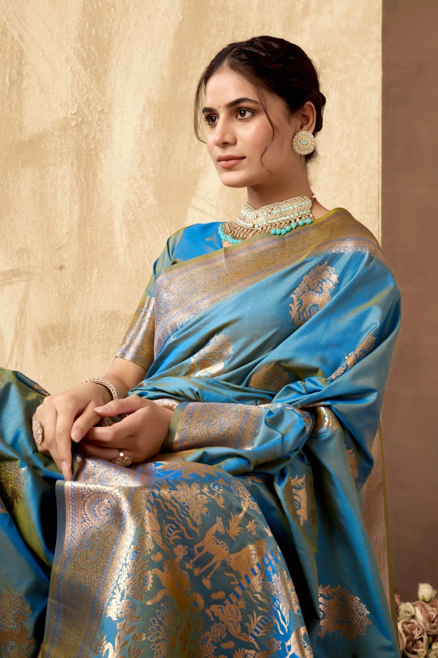 Woman wearing a blue saree with gold patterns against a beige background