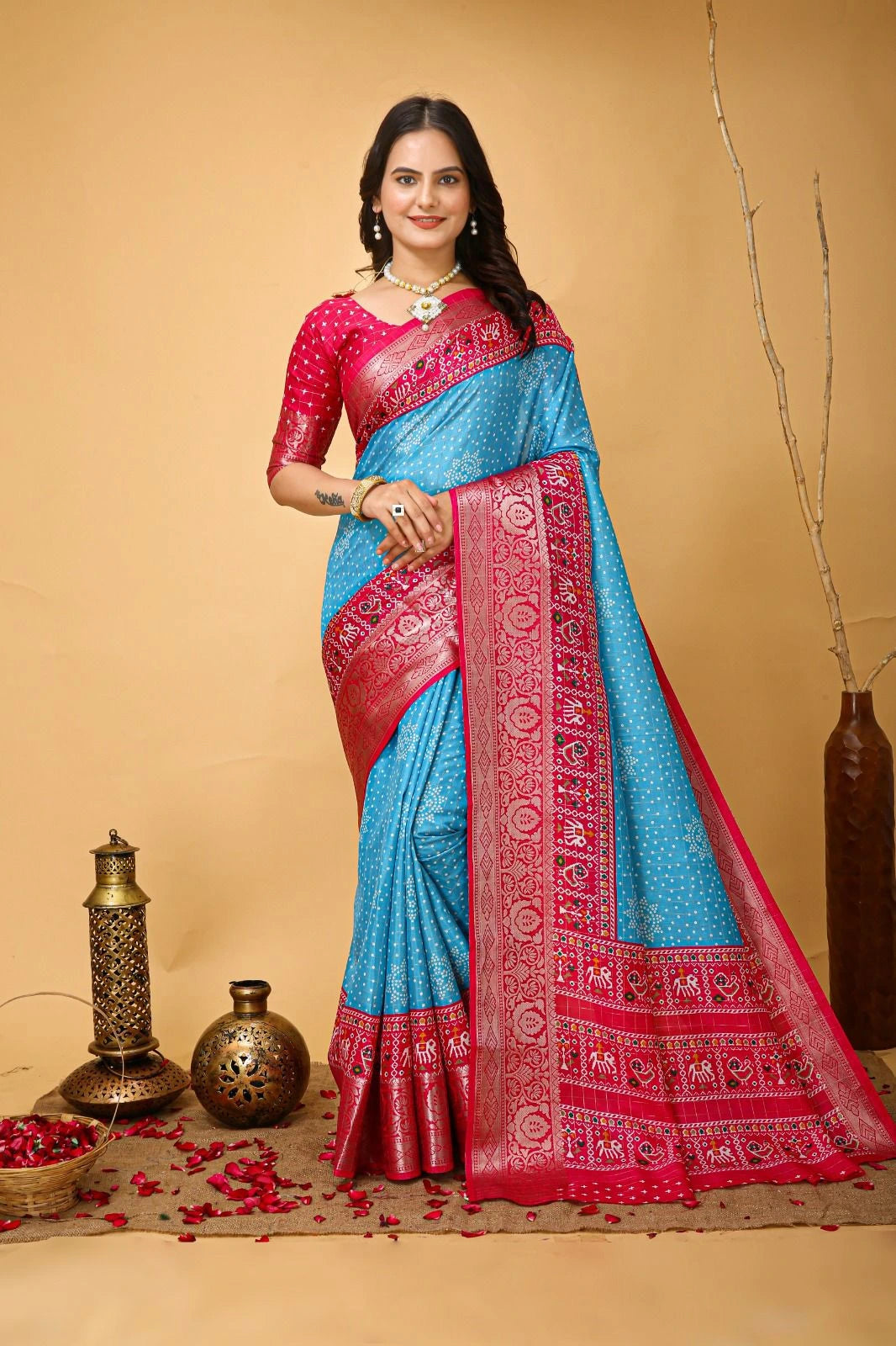 Woman wearing a blue and red saree with decorative elements on a beige background