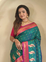 Woman wearing a green saree with pink border against a beige background