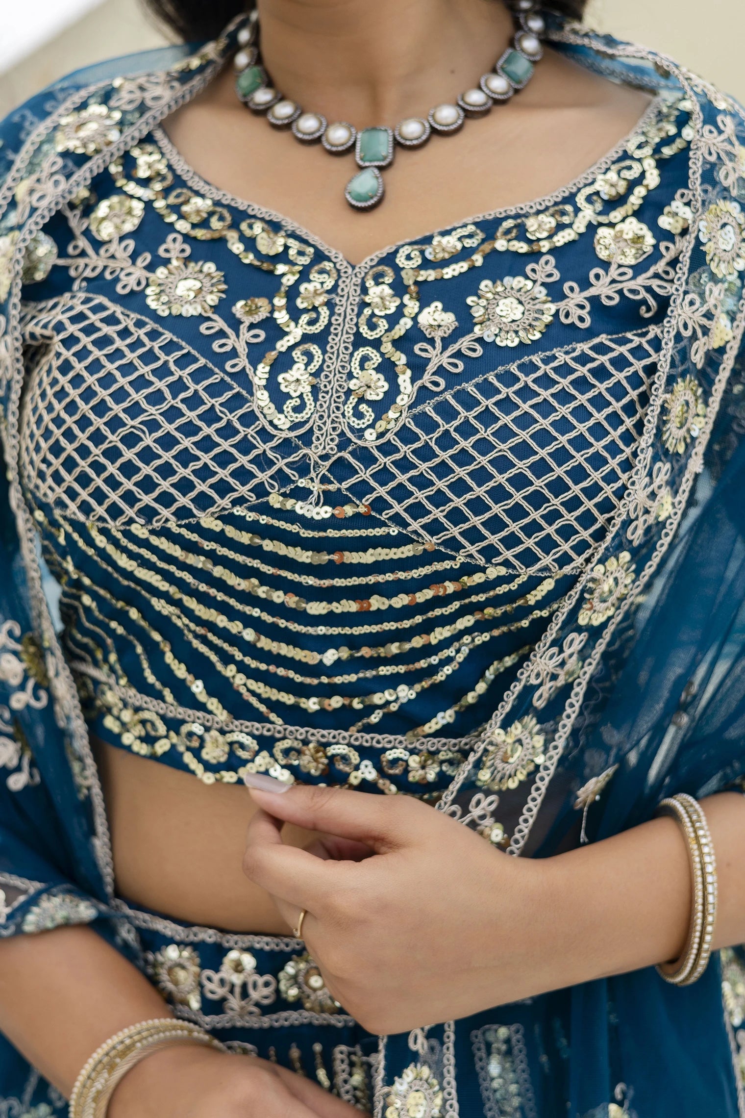 Blue embroidered traditional outfit with gold details and jewelry.