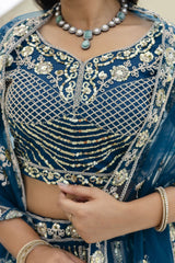 Blue embroidered traditional outfit with gold details and jewelry.