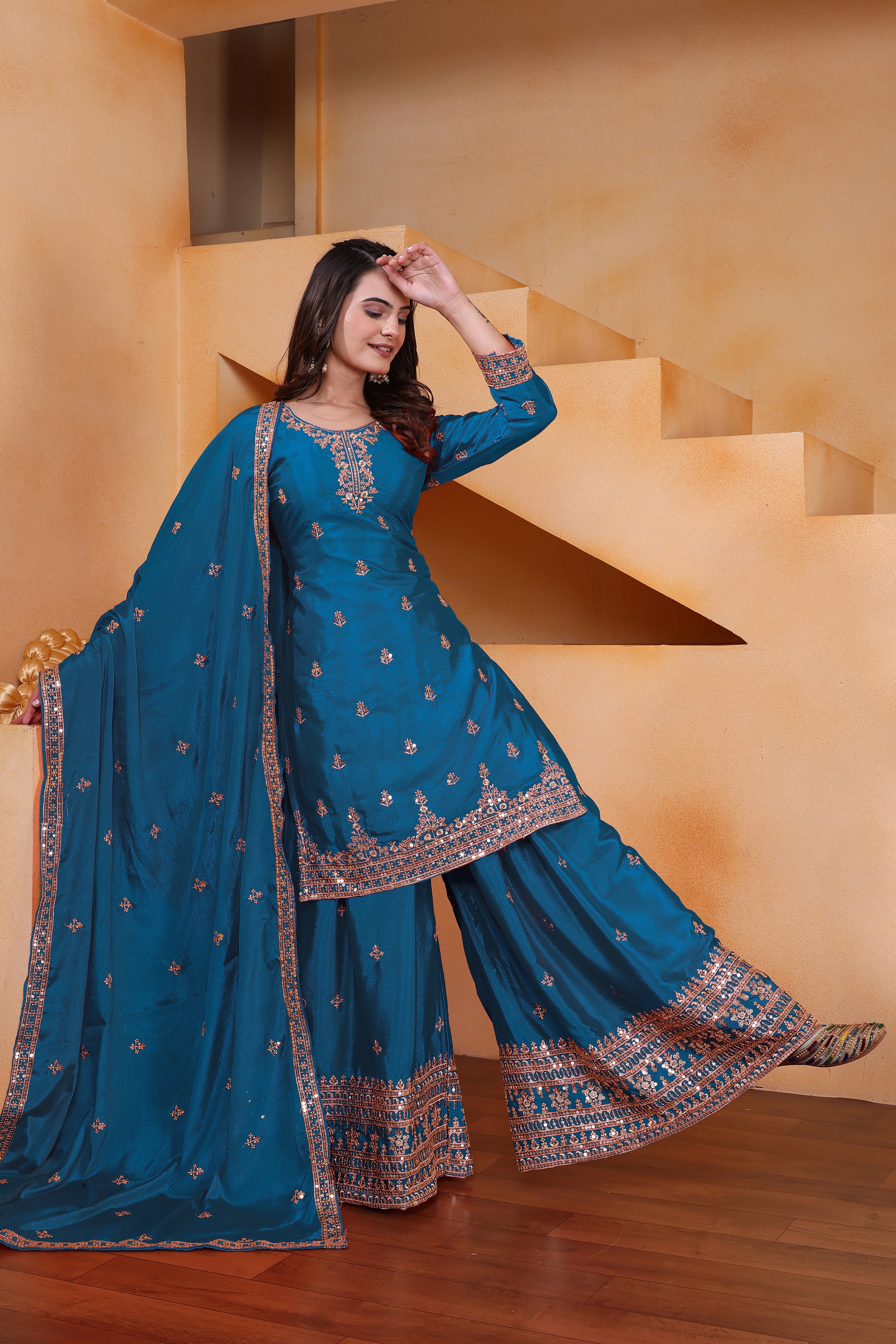 Woman in a blue traditional outfit standing on a staircase.