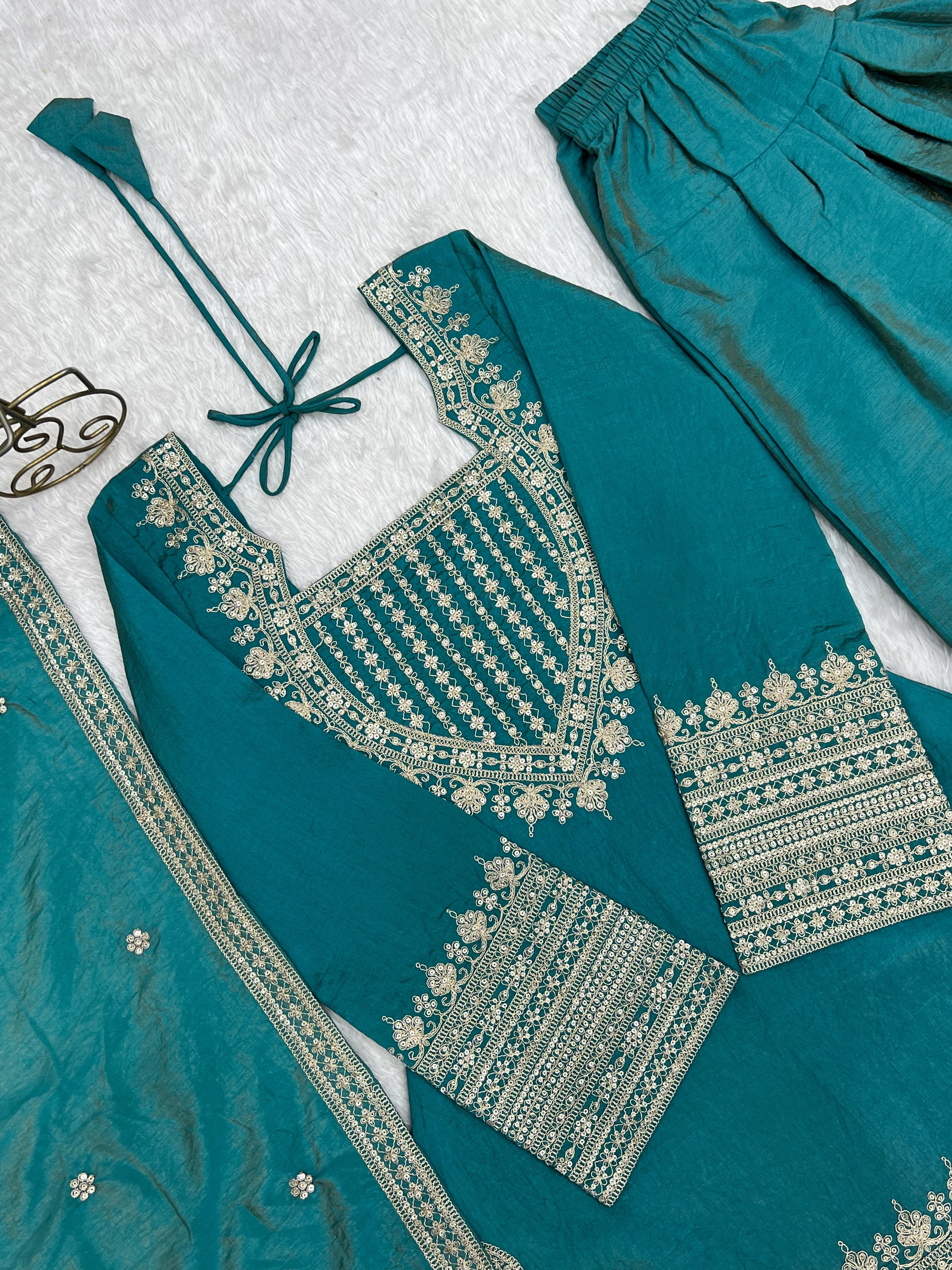 Teal traditional outfit with gold embroidery on a textured white background