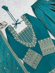 Teal traditional outfit with gold embroidery on a textured white background