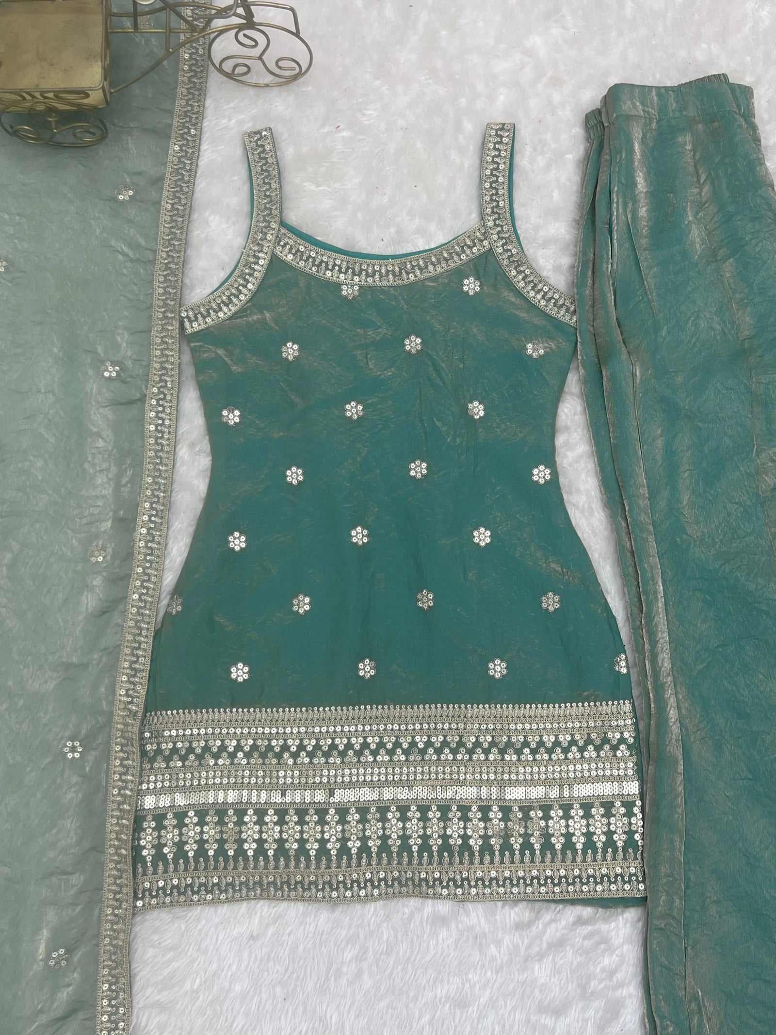 Green embroidered outfit with silver details on a textured surface