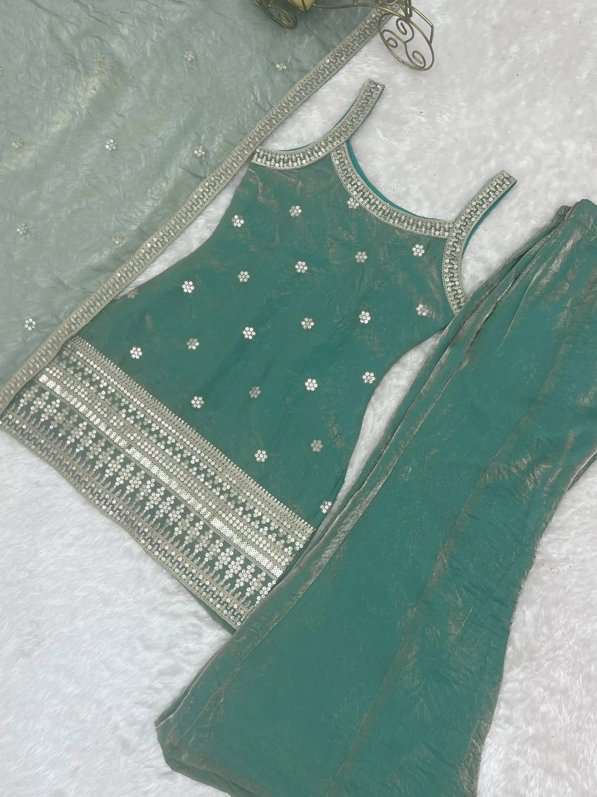 Green embroidered blouse with silver detailing on a white background