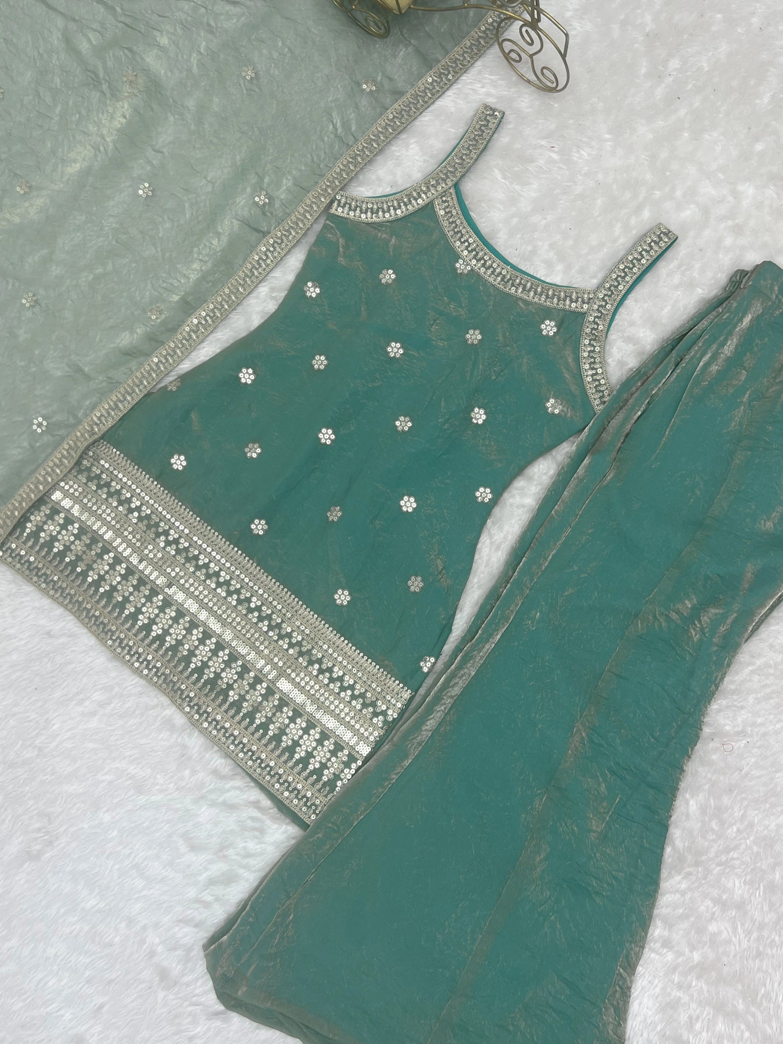 Green embroidered blouse with silver detailing on a white background