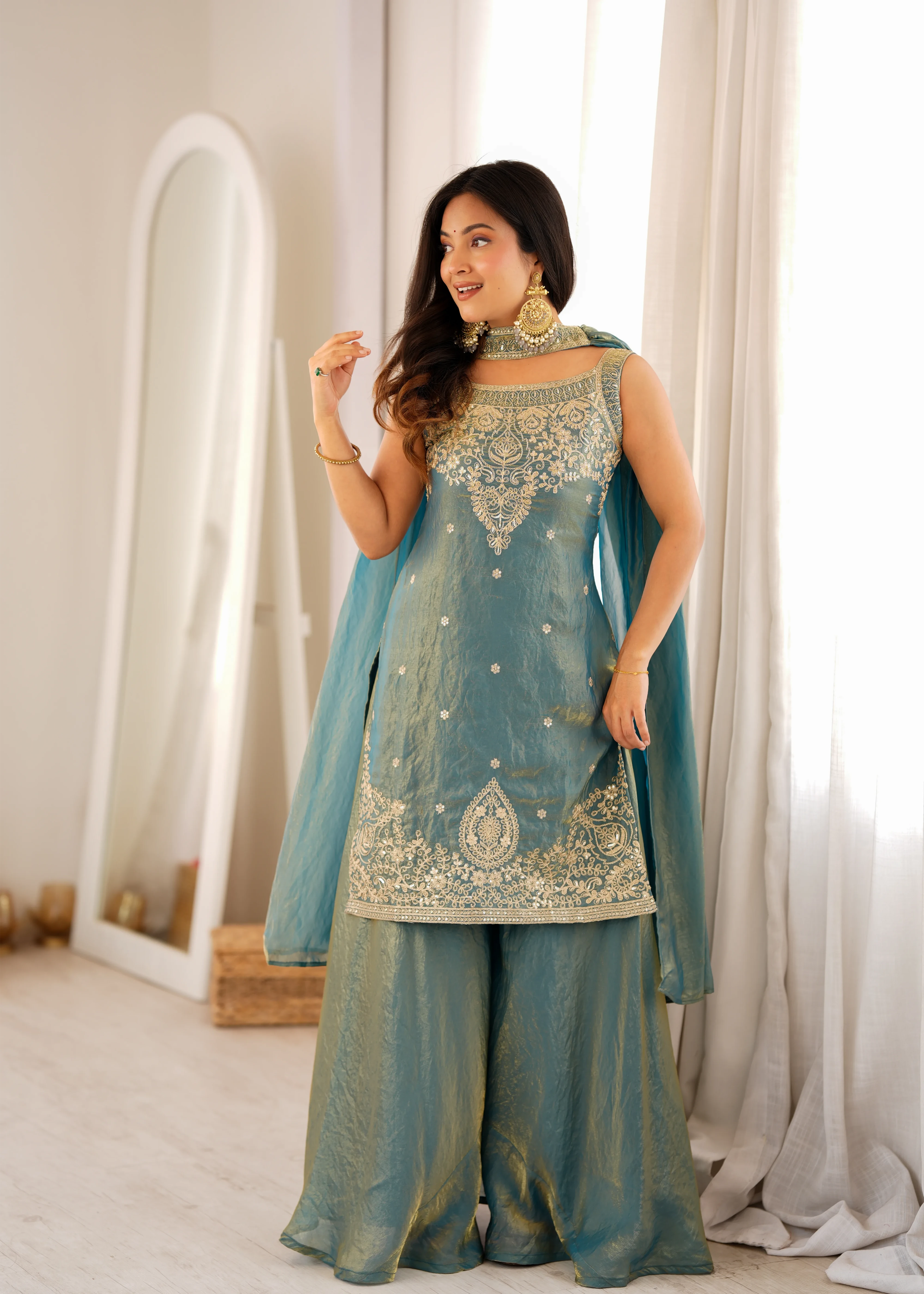 Woman wearing a traditional outfit with intricate designs in a well-lit room.