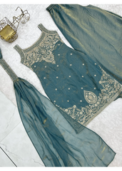 Teal traditional outfit with gold embroidery on a light gray background