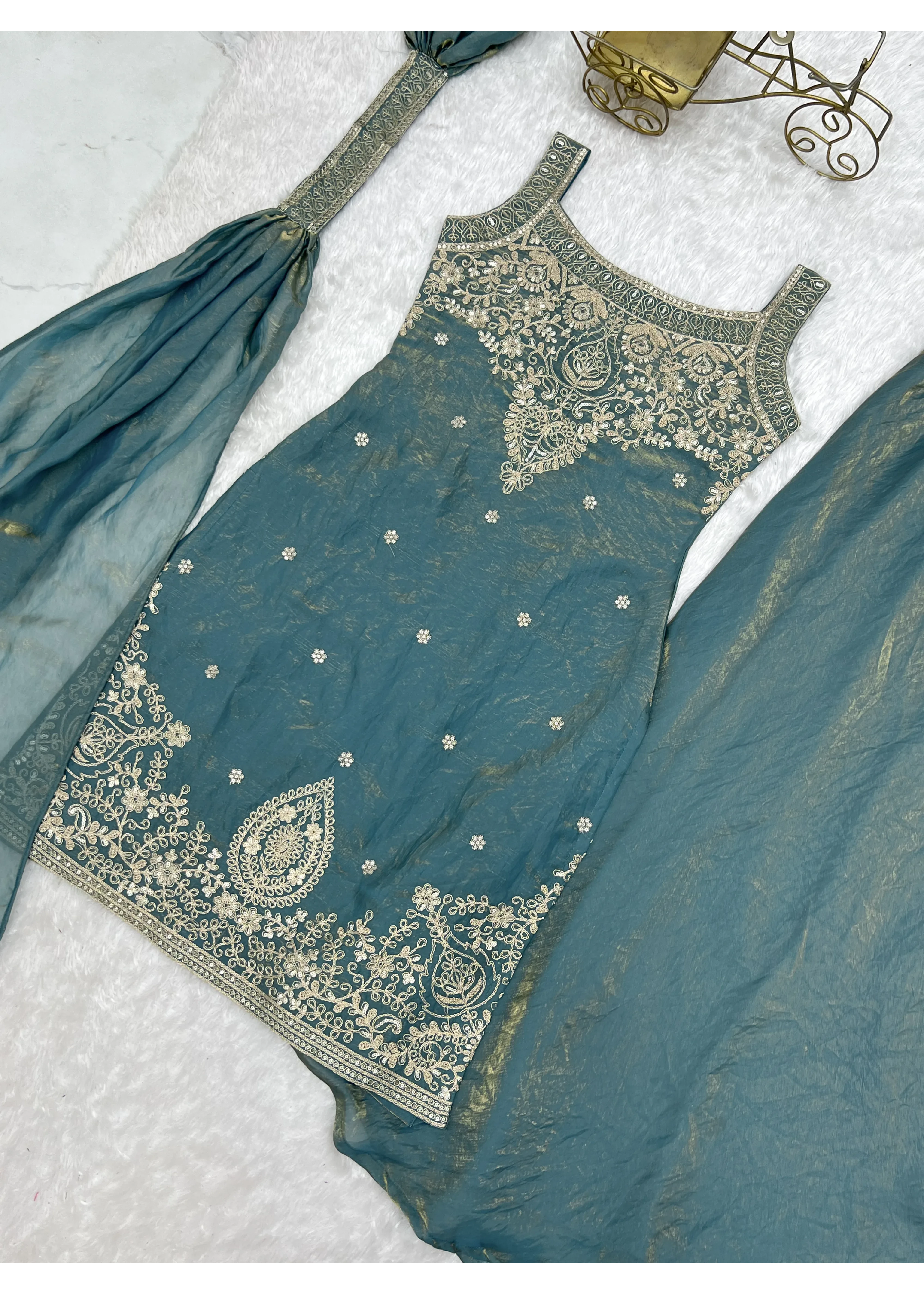 Teal embroidered traditional outfit on a light gray background