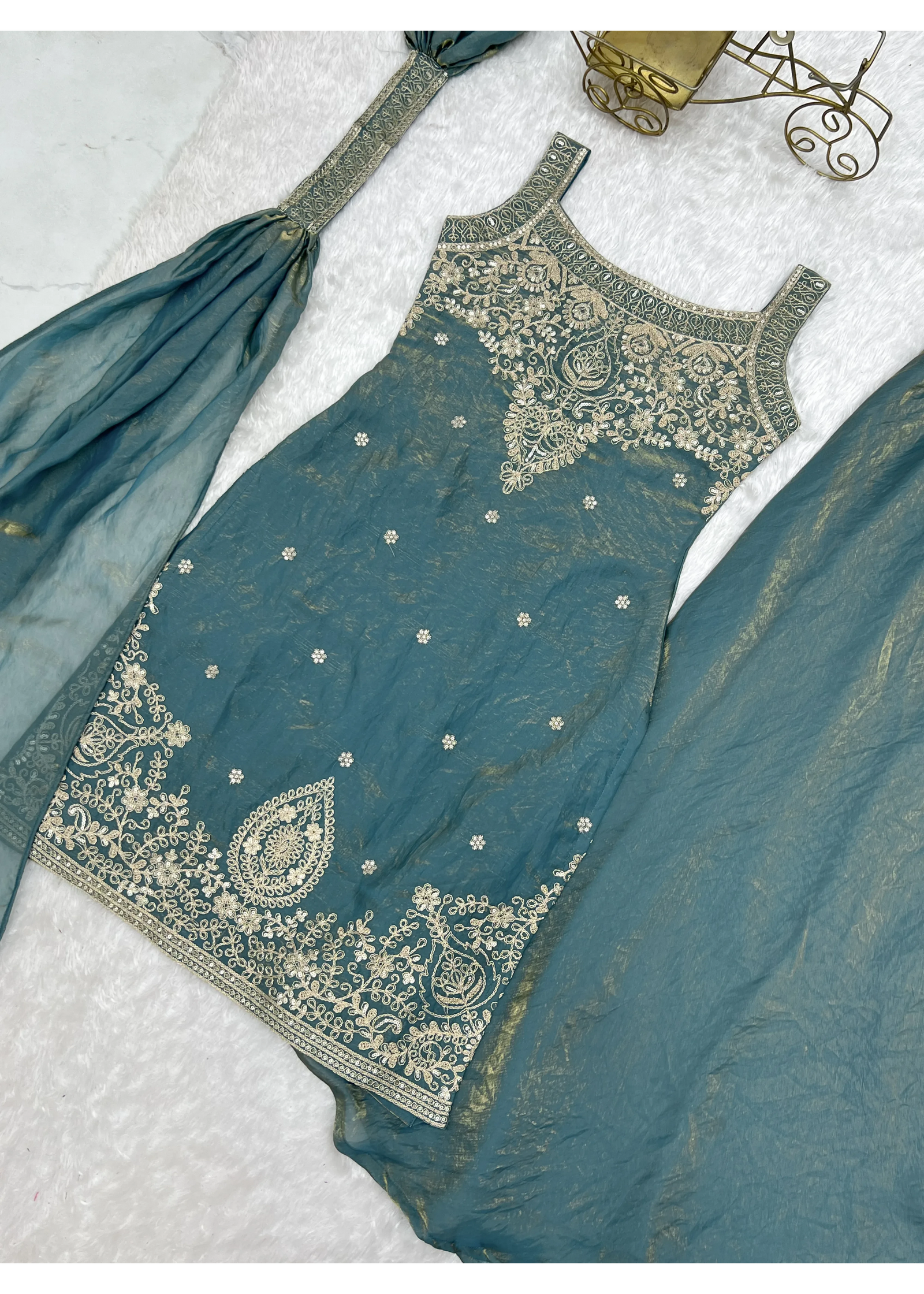 Teal embroidered traditional outfit on a light gray background