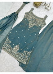 Teal embroidered traditional outfit on a light gray background