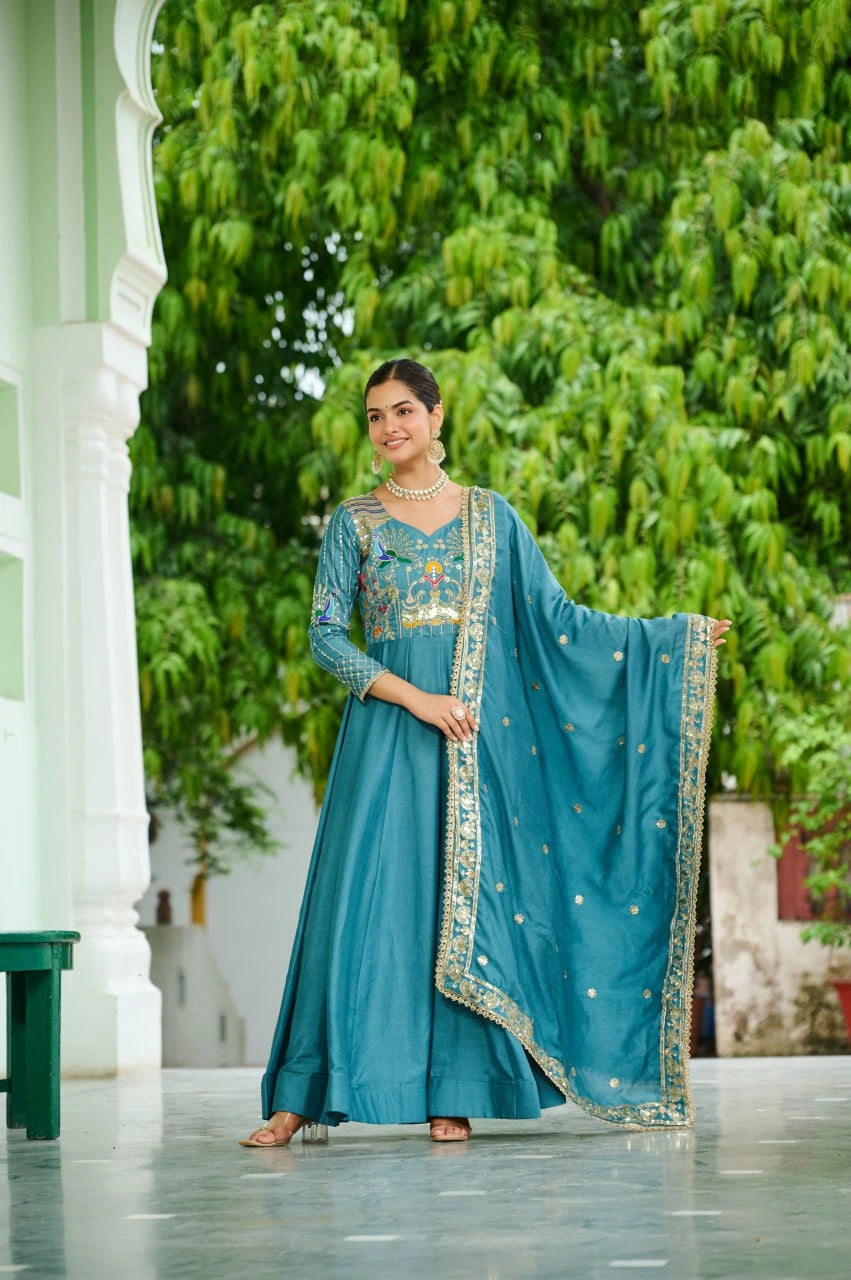 Woman in a teal traditional outfit with a matching dupatta standing outdoors.