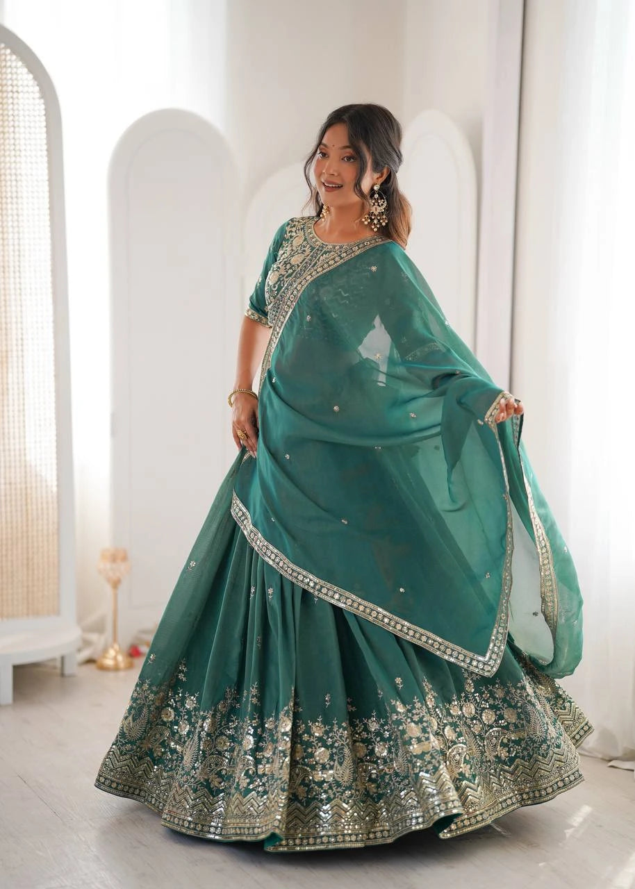 Woman wearing a teal saree with white embroidery in a minimalistic room.