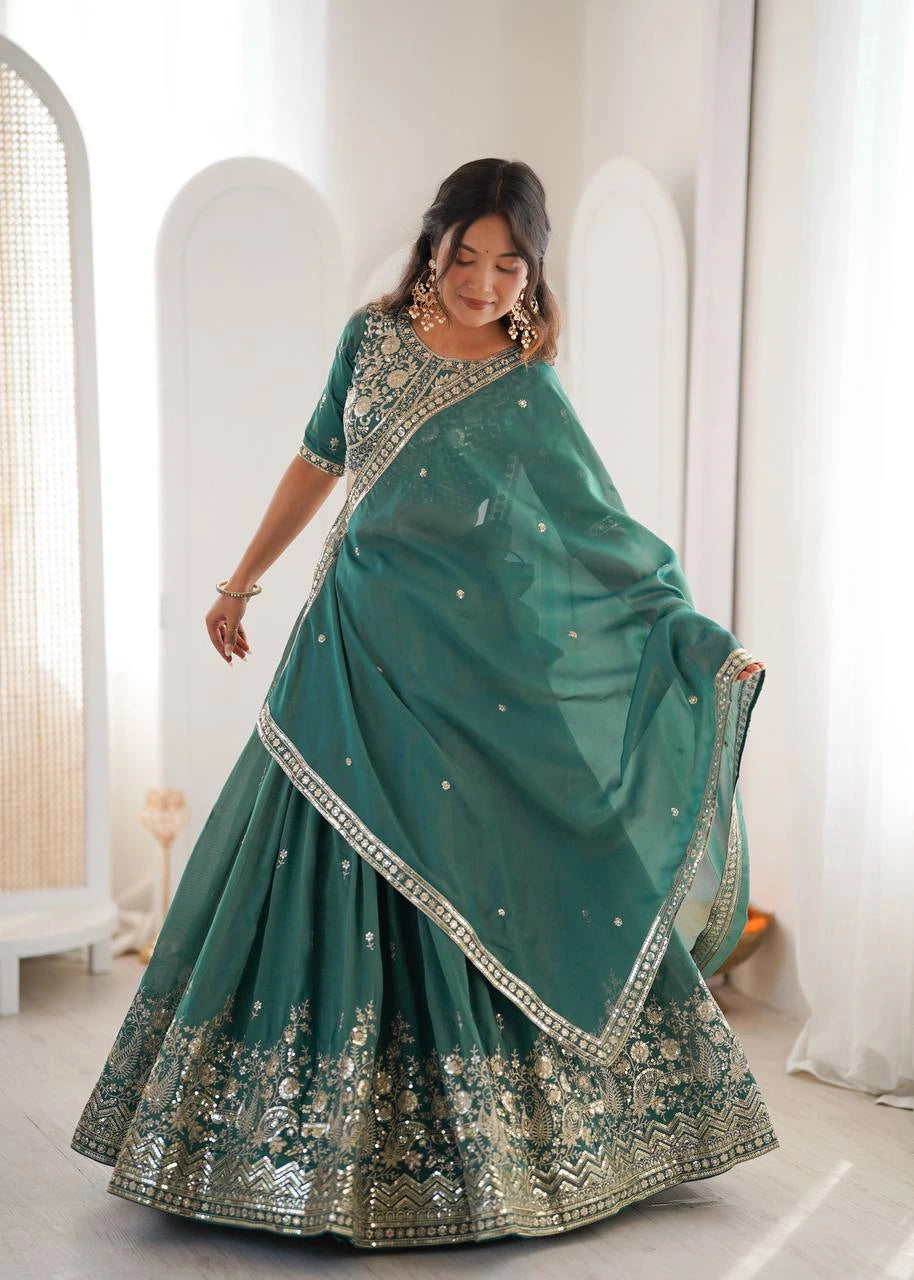 Woman wearing a teal saree with gold embroidery in a minimalistic room.