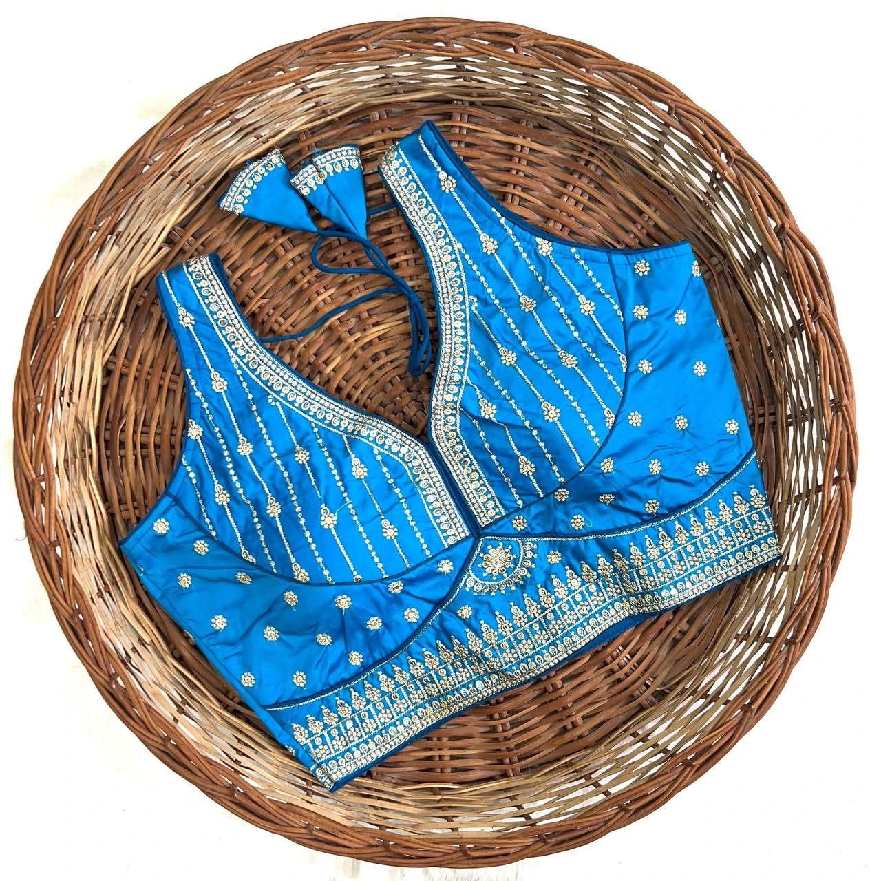 Blue embroidered blouse with a matching dupatta on a woven basket