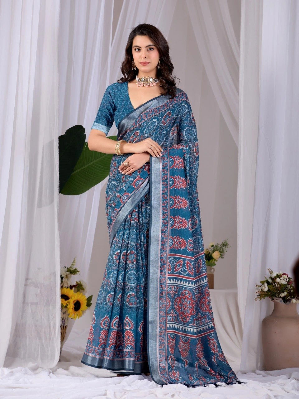 Woman wearing a blue saree with a white curtain background