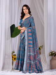 Woman wearing a blue saree with a pattern in a white draped curtain setting