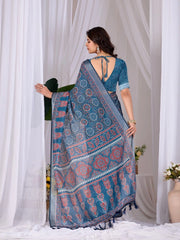 Woman holding a blue patterned saree in front of white curtains