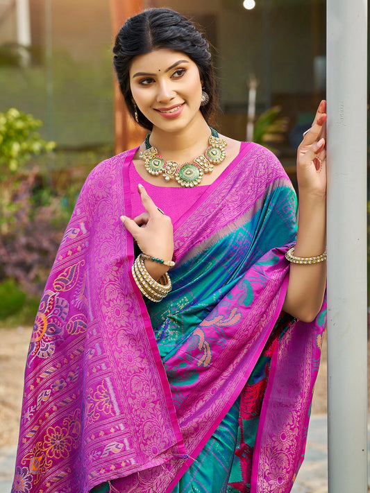 Woman wearing a colorful saree with a vibrant pink and blue pattern, standing outdoors.